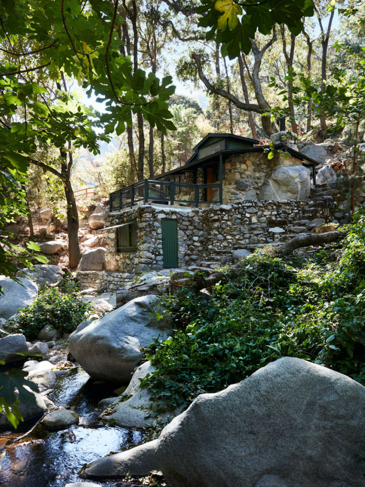 A Hollywood Directors Refined OfftheGrid Cabin by Commune Design The cabin is perched along a picturesque, boulder laden stream. The exterior remains unchanged, other than a new front door and fresh paint (Farrow & Ball Studio Green). The lower portion of the cabin is to be a bunkhouse, as yet unfinished.