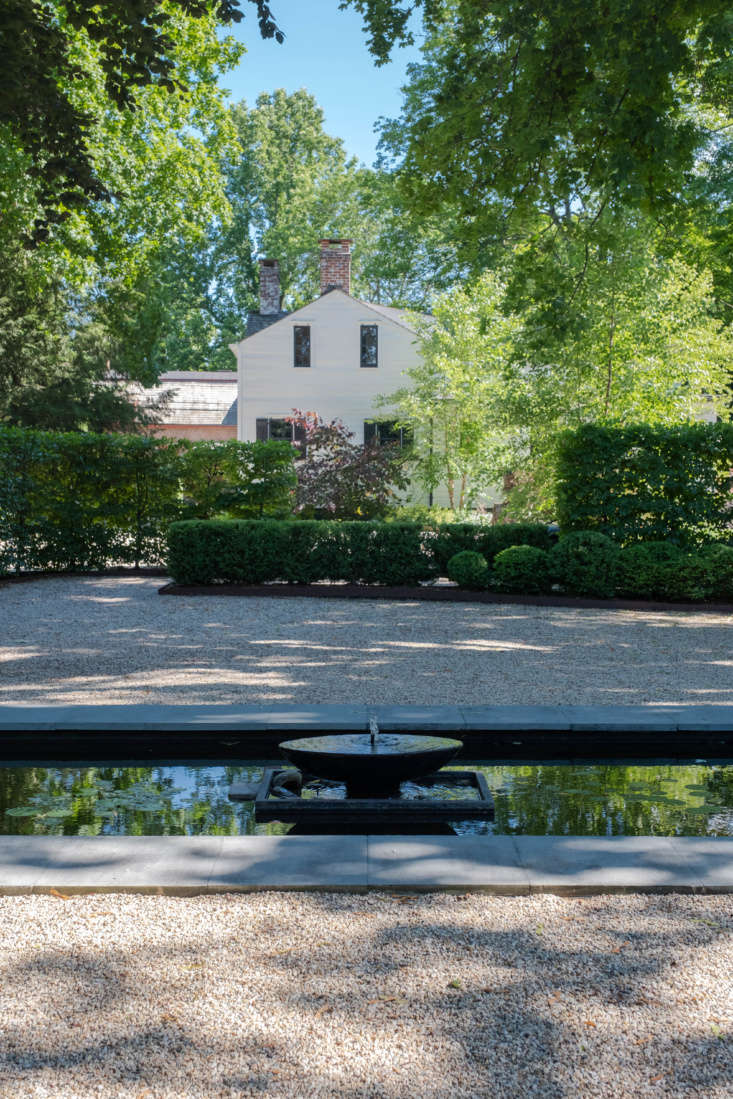 The view from the steps of the black outbuilding, looking toward the house, over the gravel courtyard and pool.