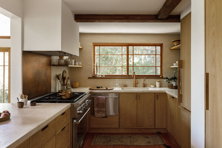 Bespoke oak wood cabinets and a copper backsplash in a kitchen designed by Tamar Barnoon. Photograph by Laure Joliet, from Before and After: A Summery Bungalow in Topanga, California, Redone by an LA Designer.