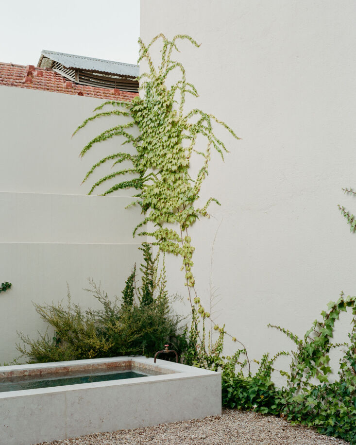 Ivy artfully creeps up the plastered walls. River pebbles keep the courtyard tidy and low-maintenance.