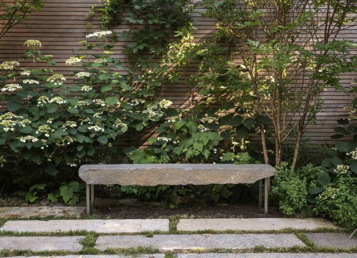Above: The bench, flanked by two crepe myrtles, is a chunk of bluestone Farris found at the stone yard and commissioned 6\18 Design to make it look like it\2\17;s floating. Farris says the design of the clear cedar fence (a sustainable wood) was inspired by a project by Tom Stuart Smith.