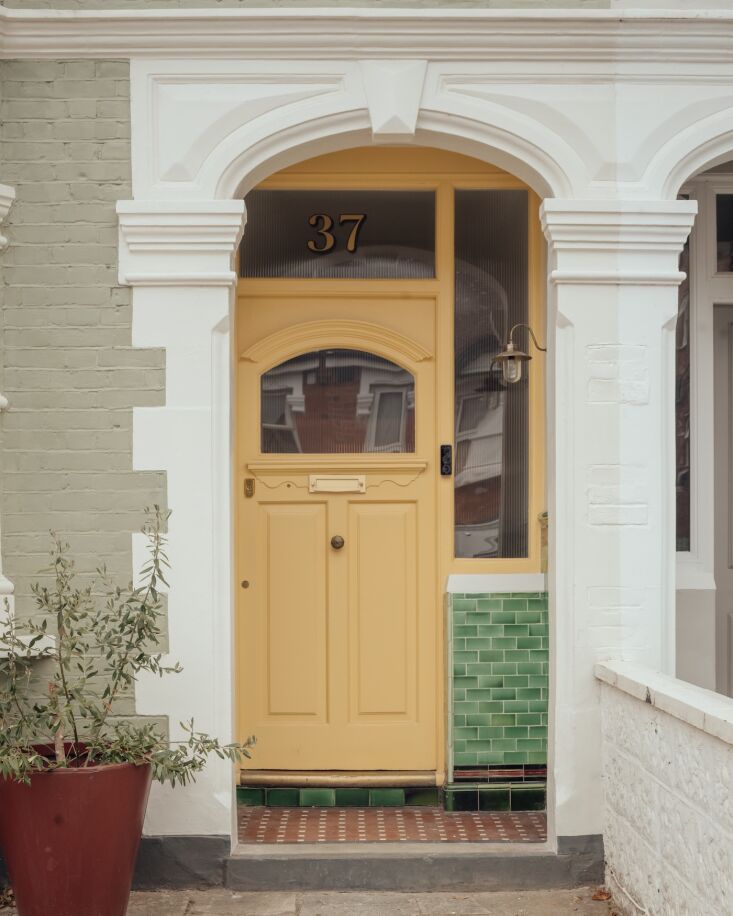 Tiles in different shades and patterns paired with sunny yellow paint make for a winning front-door scene. (The period-appropriate linseed paint is from Brouns & Co.) Photograph by Jim Stephenson, courtesy of Atelier Baulier, from Business Up Front, Party in the Back: A Creative, Eco-Friendly House Update in West London.